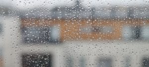 Kuva naapuritalosta sateen kasteleman ikkunan läi